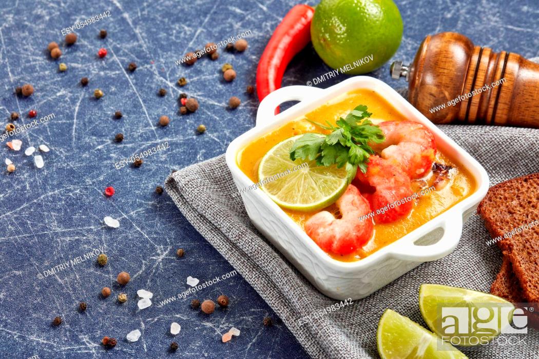 Stock Photo: Delicious fish cream soup with shrimps in white bowl served with spices, lime and pieces of bread on dark blue marble background. Healthy food.