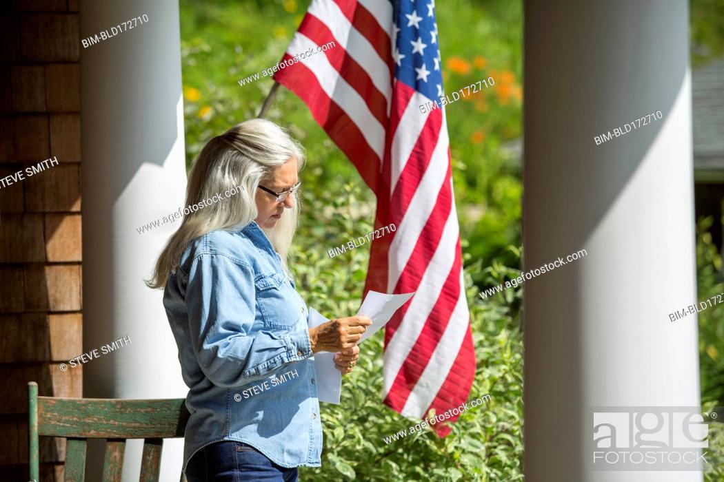 Stock Photo: Caucasian woman reading letter on porch.