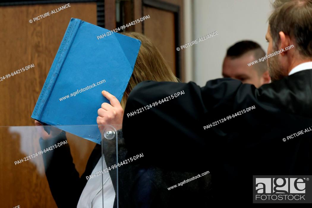 Stock Photo: 24 November 2022, North Rhine-Westphalia, Mönchengladbach: The defendant covers her face with a blue folder as she is led into the courtroom at the regional.
