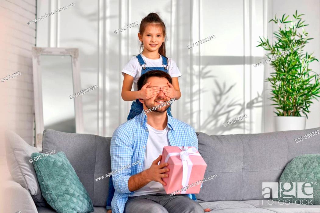 Stock Photo: cute daughter congratulates her father and gives him gift box. happy dad and little child girl.
