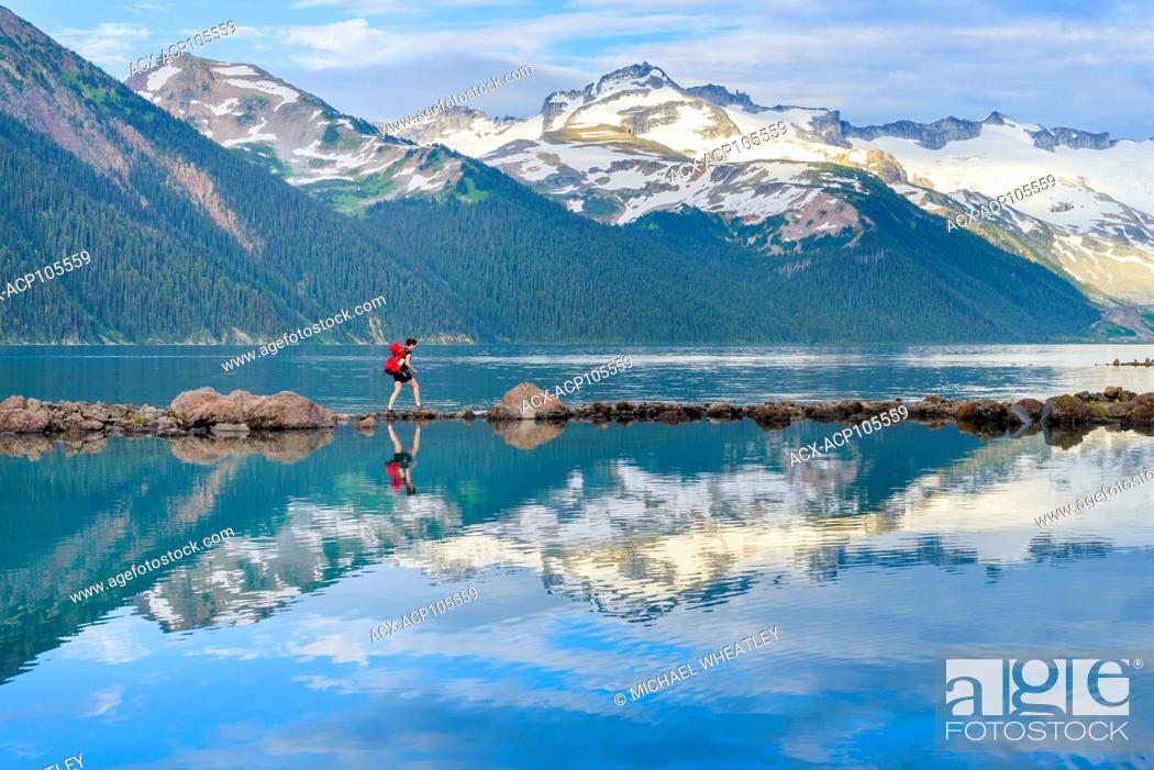 Stock Photo: Woman navigates rock stepping stones at Garibaldi Lake, Garibaldi Provincial Park, British Columbia, Canada.