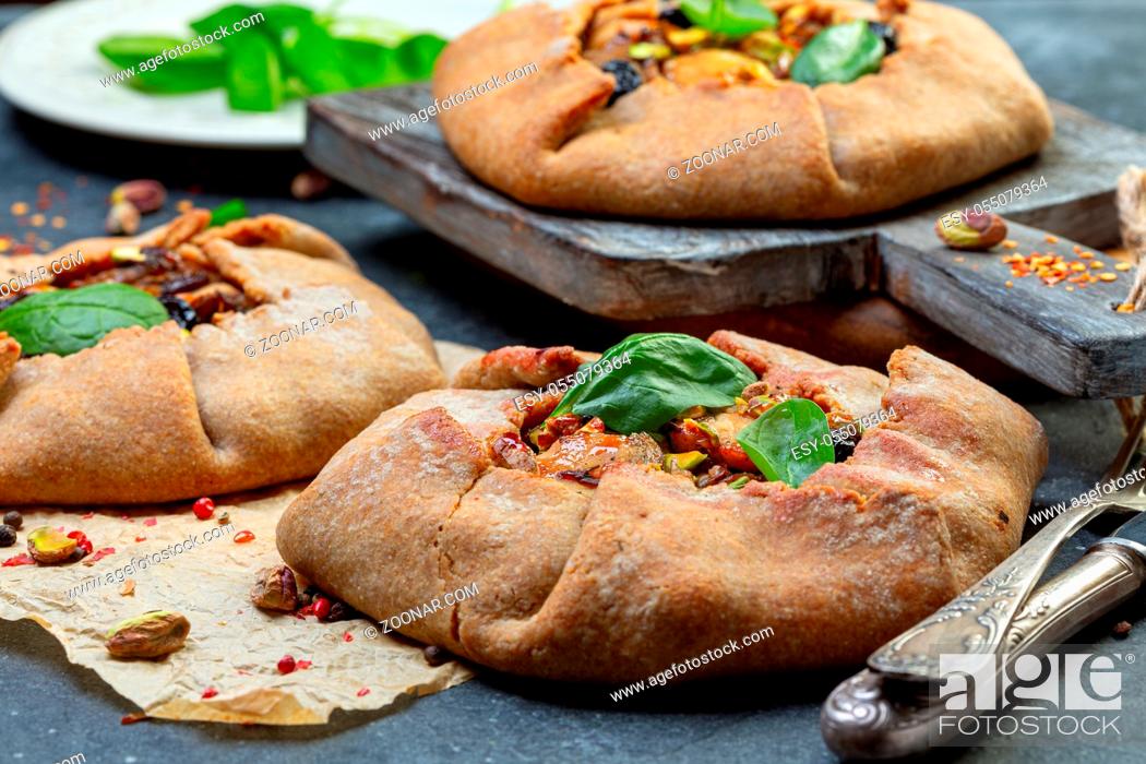Stock Photo: Open pies (galette) with chicken, onion and mushrooms served with green spinach and pistachios, selective focus.