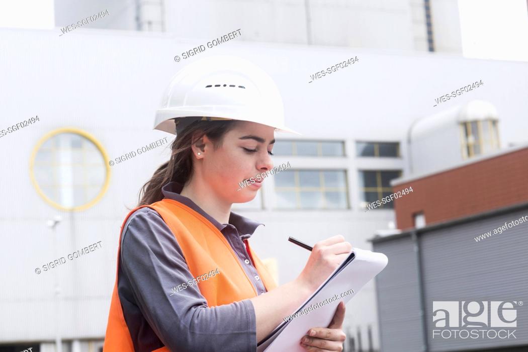 Photo de stock: Female worker with clipboard taking notes at power plant.