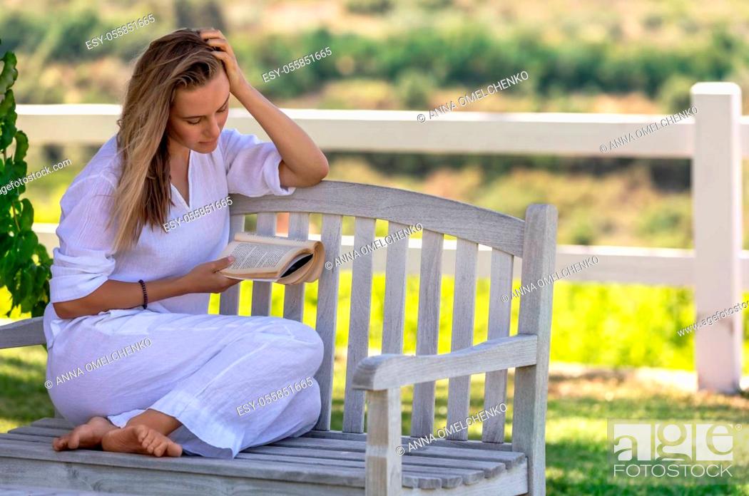 Stock Photo: Beautiful Young Woman Sitting on the Bench in the Park and Reading a Book. Spending Nice Summer Day with Good Story. Peace and Relaxation Concept.