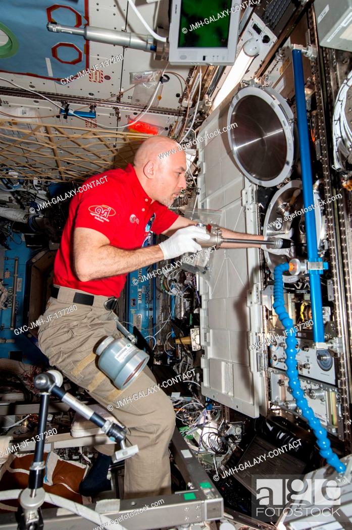 Stock Photo: European Space Agency astronaut Luca Parmitano, Expedition 37 flight engineer, works with the Combustion Integrated Rack (CIR) Multi-user Drop Combustion.
