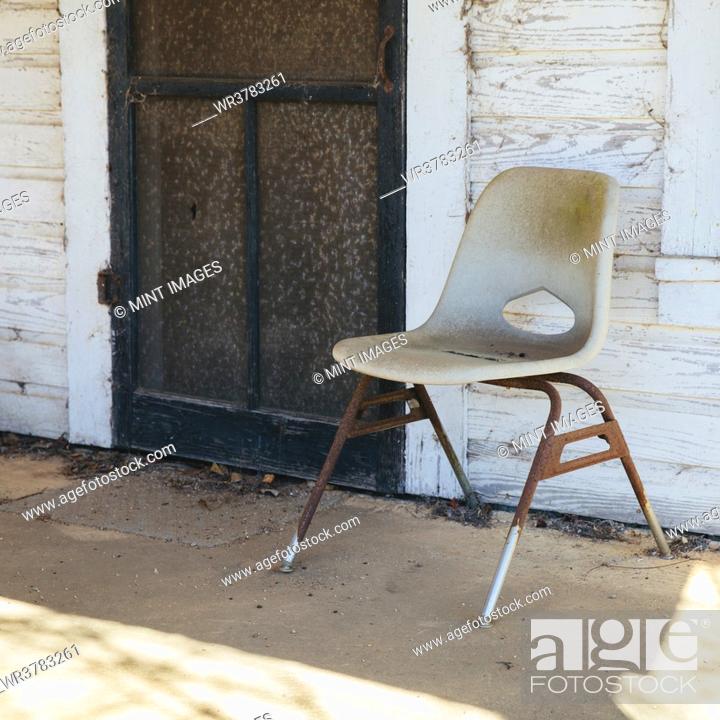 Stock Photo: Chair on the porch by a door of old building.