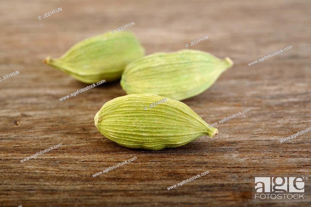 Stock Photo: green cardamom pods on wooden background.