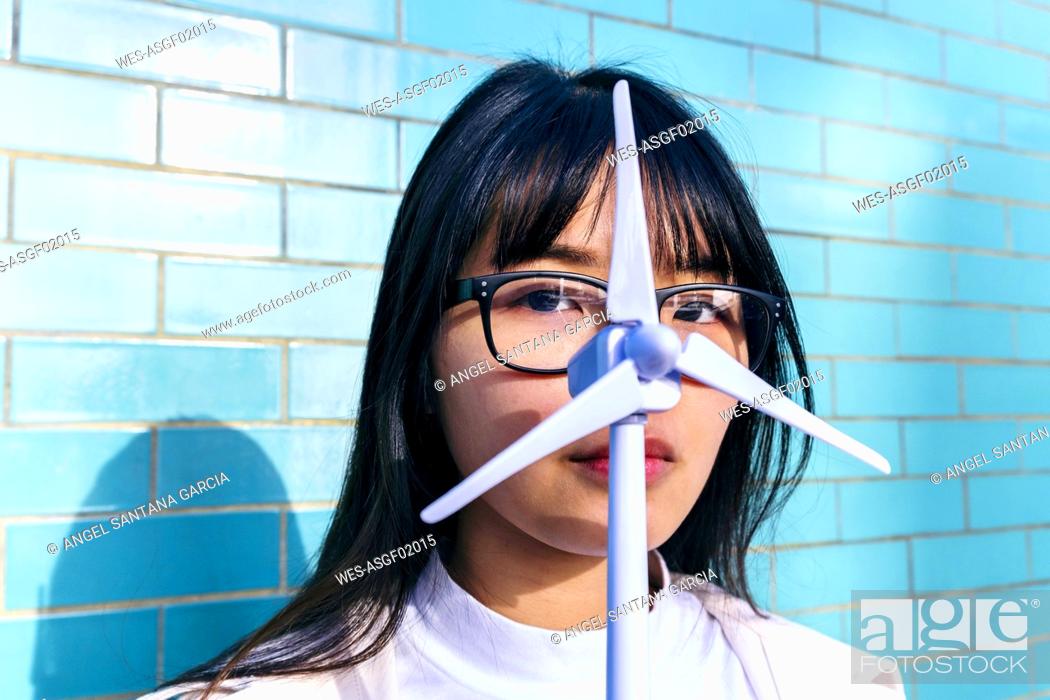 Imagen: Young woman with eyeglasses holding wind turbine toy in front of face.