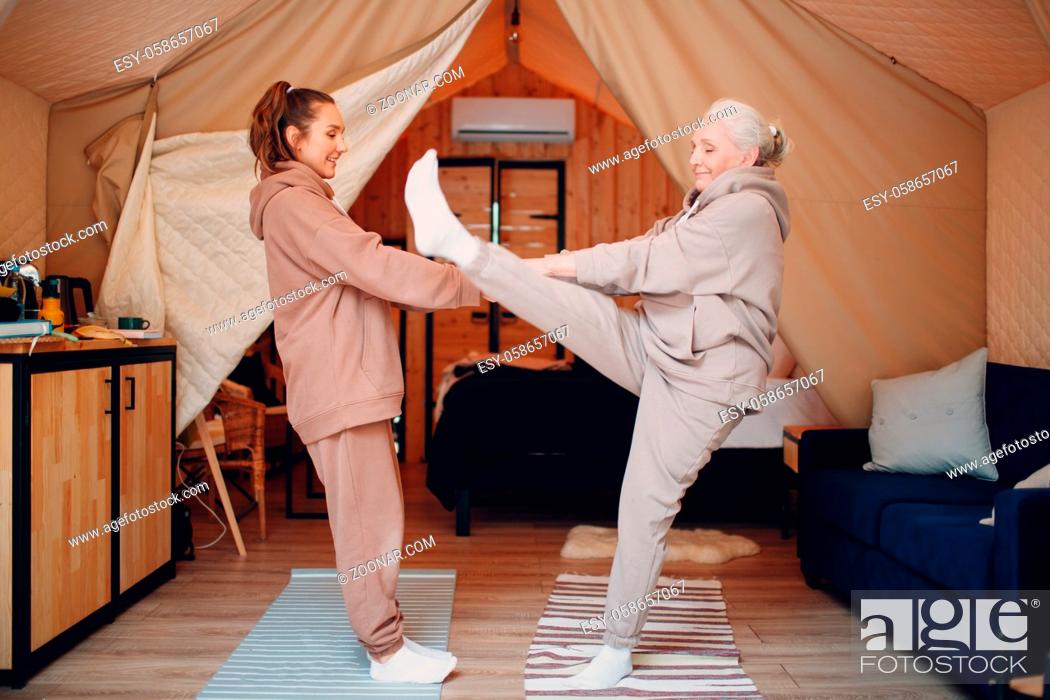 Stock Photo: Family doing warming up exercises sports indoors. Young and senior elderly woman relaxing at glamping camping tent. Mother and daughter modern at fitness.