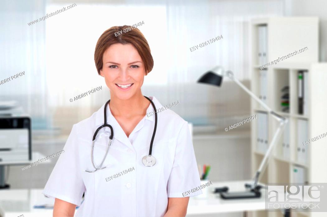 Stock Photo: Portrait of beautiful young female doctor smiling over white background.