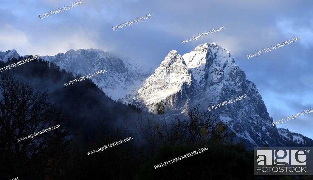 Stock Photo: 02 November 2021, Bavaria, Garmisch-Partenkirchen: Freshly covered with snow after the night, the summits of the Wetterstein Mountains with the Zugspitze (l).