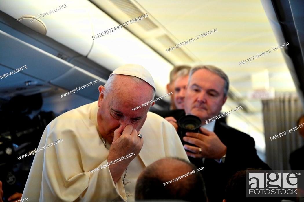 Stock Photo: 24 July 2022, ---: Pope Francis (l) holds his nose as he speaks on the plane. The pope is setting off on a difficult trip to Canada.