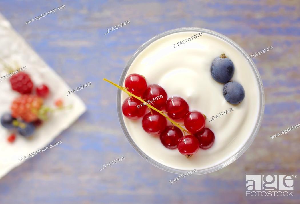 Stock Photo: Fruit of the forest with yoghurt on a blurred blue table background.