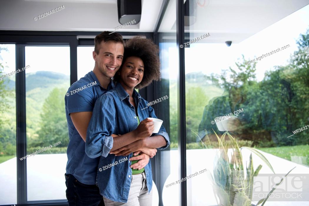 Stock Photo: romantic happy young multiethnic couple enjoying morning coffee by the window in their luxury home.