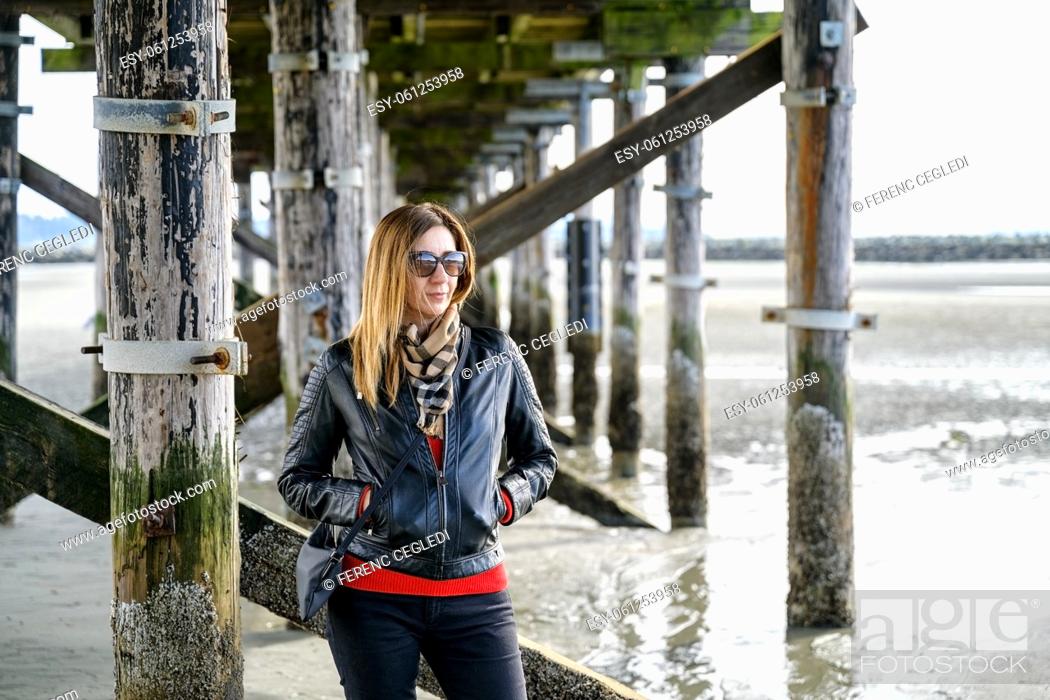 Stock Photo: Stylish, well-dressed casual middle-aged woman looking sideway and standing underneath Canada's longest pier, the 470-metre-long White Rock Pier in White Rock.
