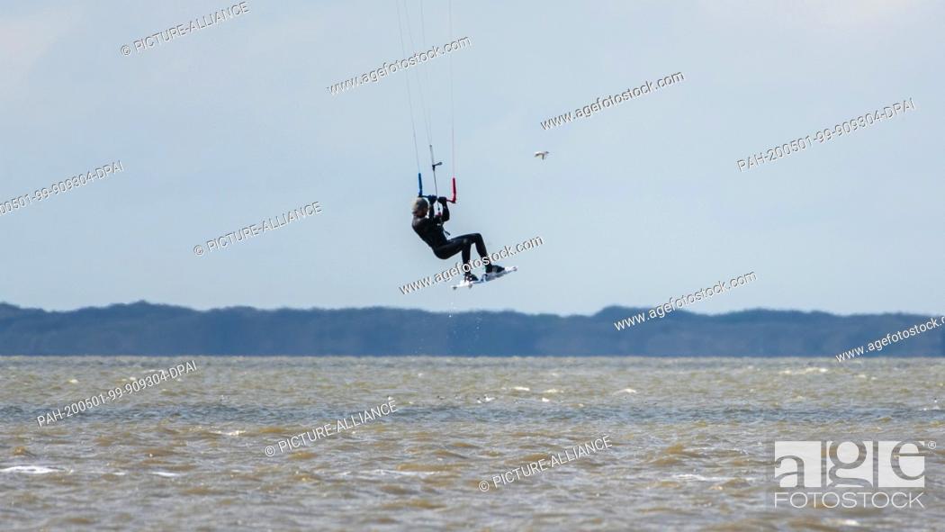 Stock Photo: 01 May 2020, Lower Saxony, Norddeich: Kitesurfer Louis Urfel in the afternoon in the North Sea near Norddeich. Photo: Mohssen Assanimoghaddam/dpa.