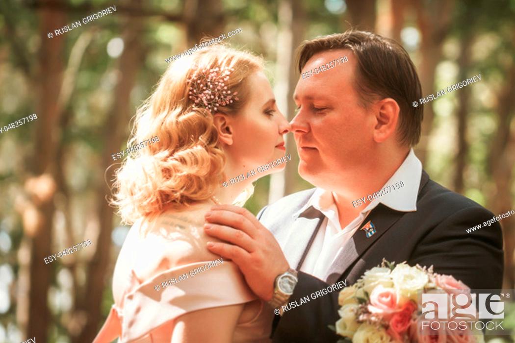 Photo de stock: bride and groom kiss on the background of trees and forest.