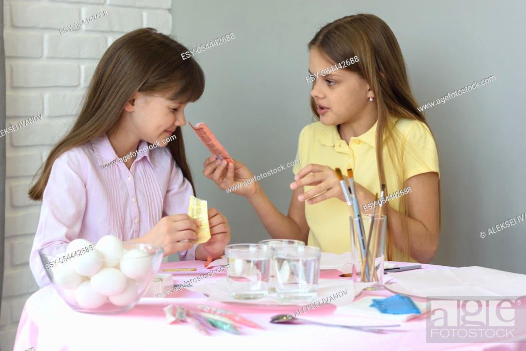 Stock Photo: A girl shows the other girl the contents of a bag of food coloring.