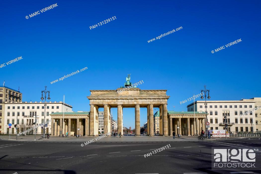 Stock Photo: 23.03.2020, the Brandenburg goal in Berlin on a late spring juice day in the low sun. Due to the corona crisis, only a few people are on the streets and squares.