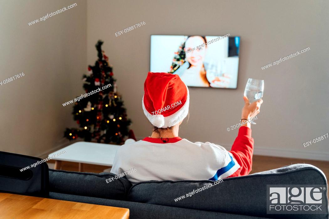 Stock Photo: Millennial young woman using phone at home in Christmas Eve. Online holiday shopping, quarantine virtual celebration . High quality photo.