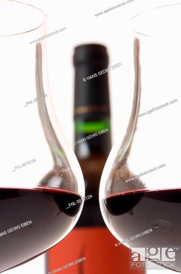 Stock Photo: Two filled claret glasses in front of wine bottle, cross-section.