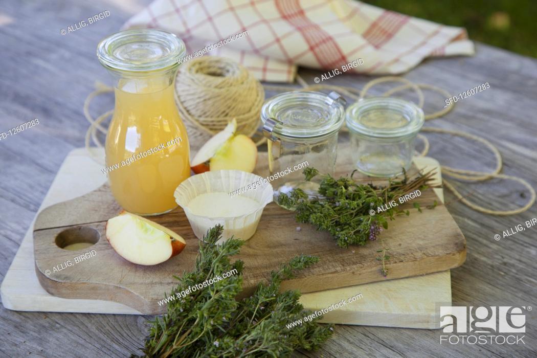 Stock Photo: Ingredients and glass jars for thyme jelly with apple juice on a wooden table.