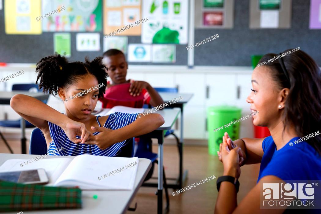 Stock Photo: African american female teacher and a girl talking in hand sign language at elementary school.