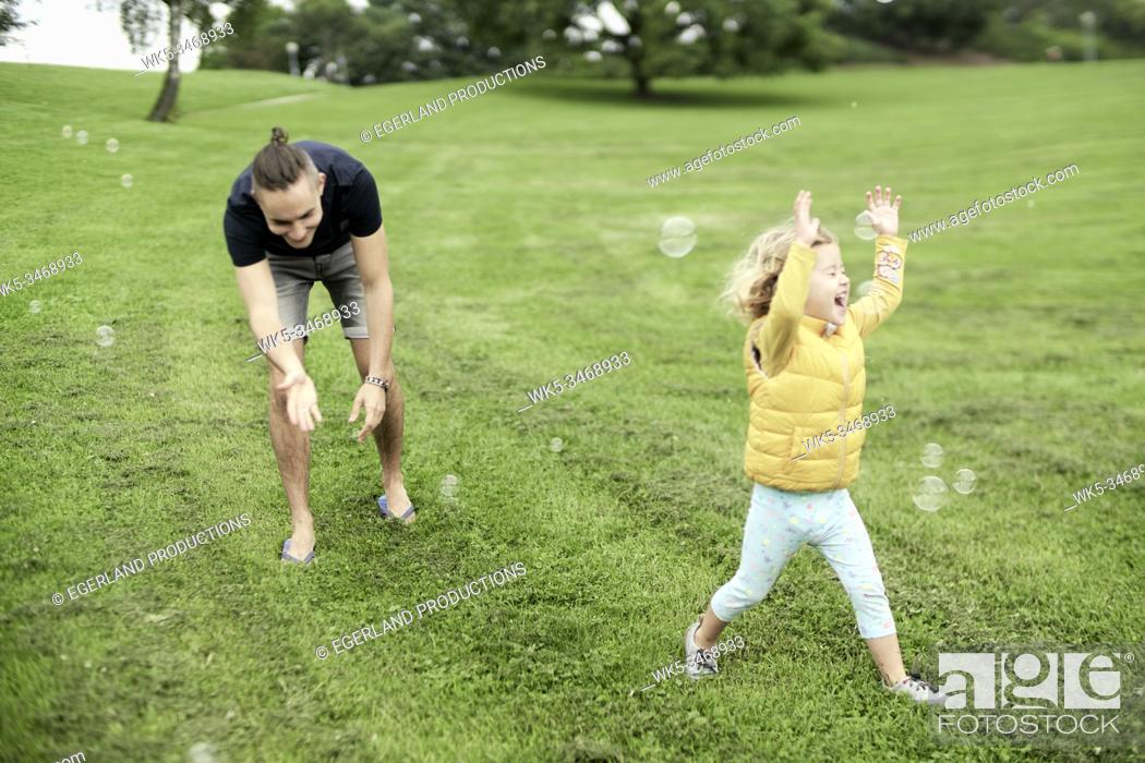 Stock Photo: Family blowing bubbles in park. Munich, Germany.