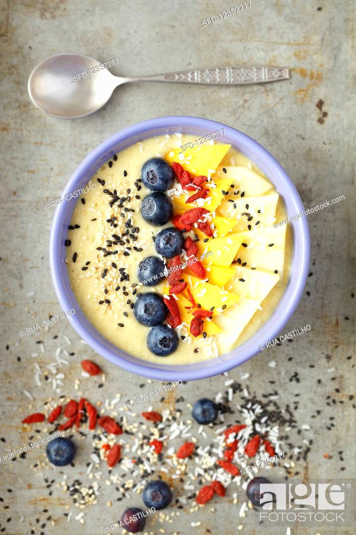 Stock Photo: A tropical smoothie bowl with mango, pineapple, goji berries and coconut milk.