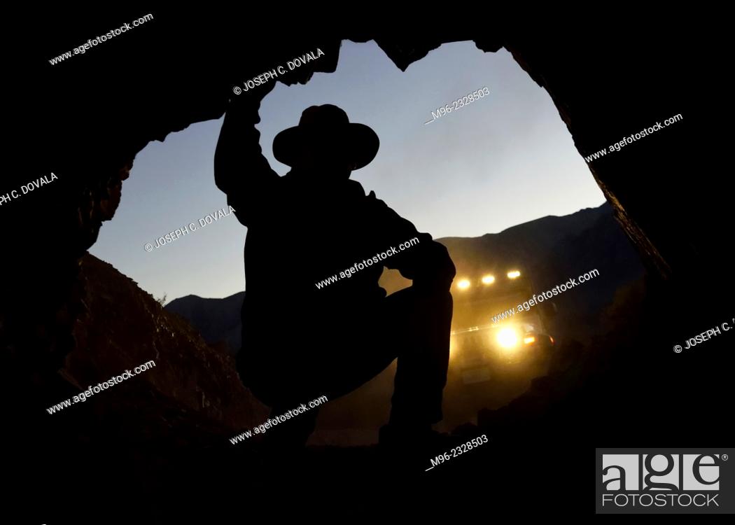 Stock Photo: Man looking inside mine entrance, Mojave Desert, California, USA.