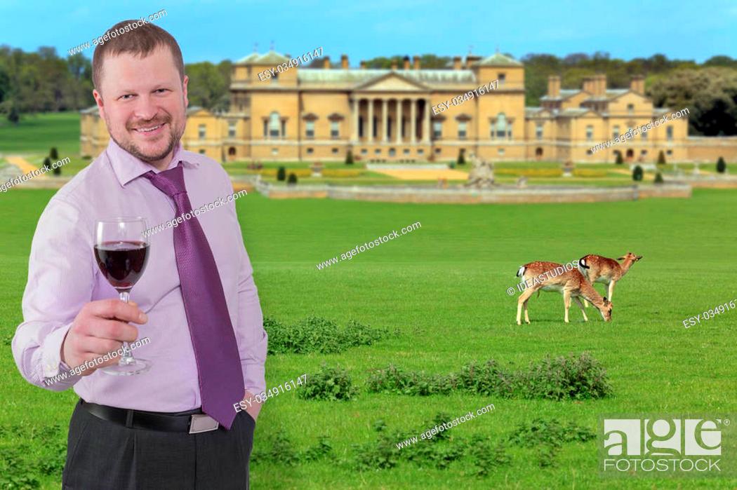 Stock Photo: Businessman holding glass of wine and beautiful villa in background.