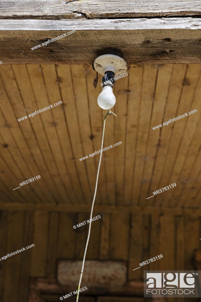 Stock Photo: Old incandescent light bulb on a porch beam with a string pull control.