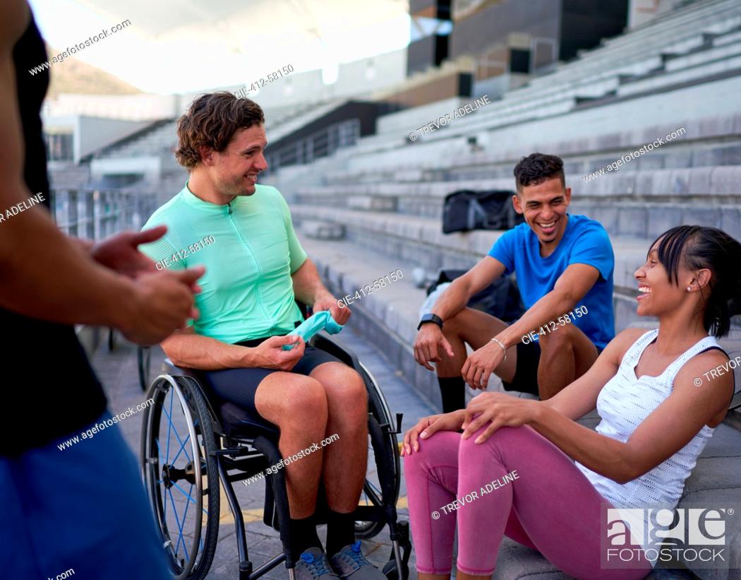 Imagen: Happy athletes laughing and talking in bleachers.