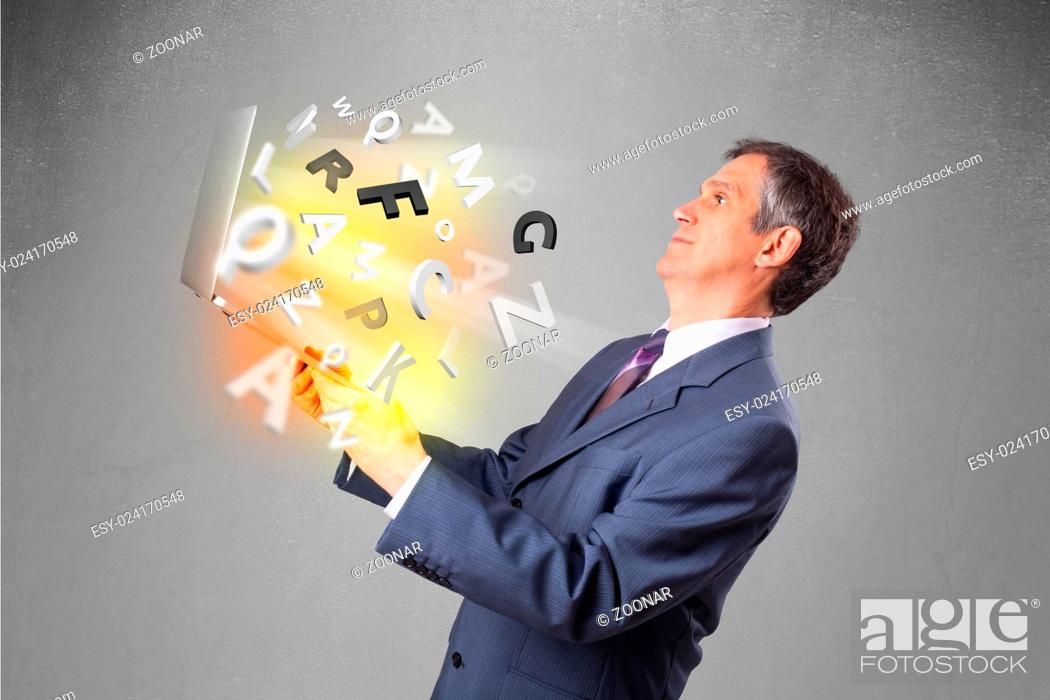 Stock Photo: Middle aged businessman holding laptop with colorful letters.