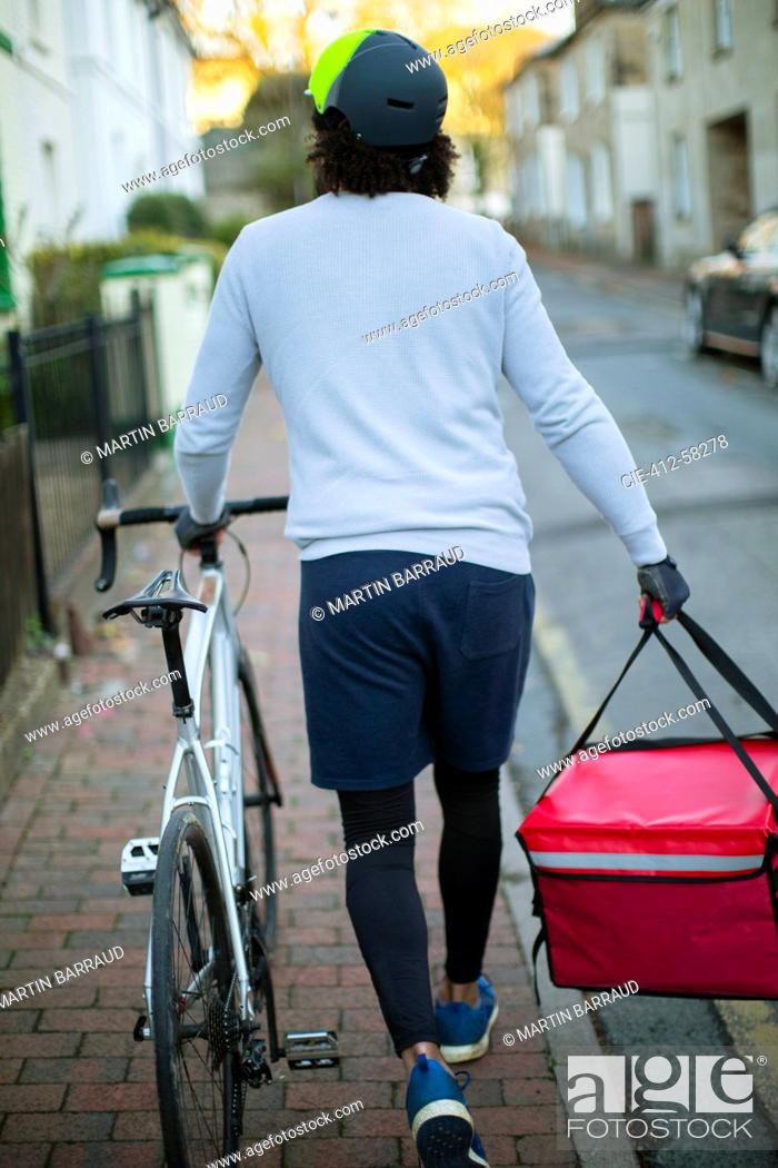 Photo de stock: Male bike messenger delivering food in urban neighborhood.