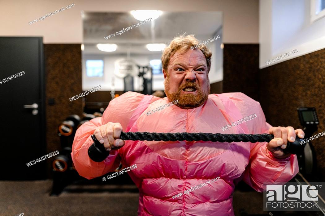 Stock Photo: Man wearing pink bodybuilder costume practicing in gym.