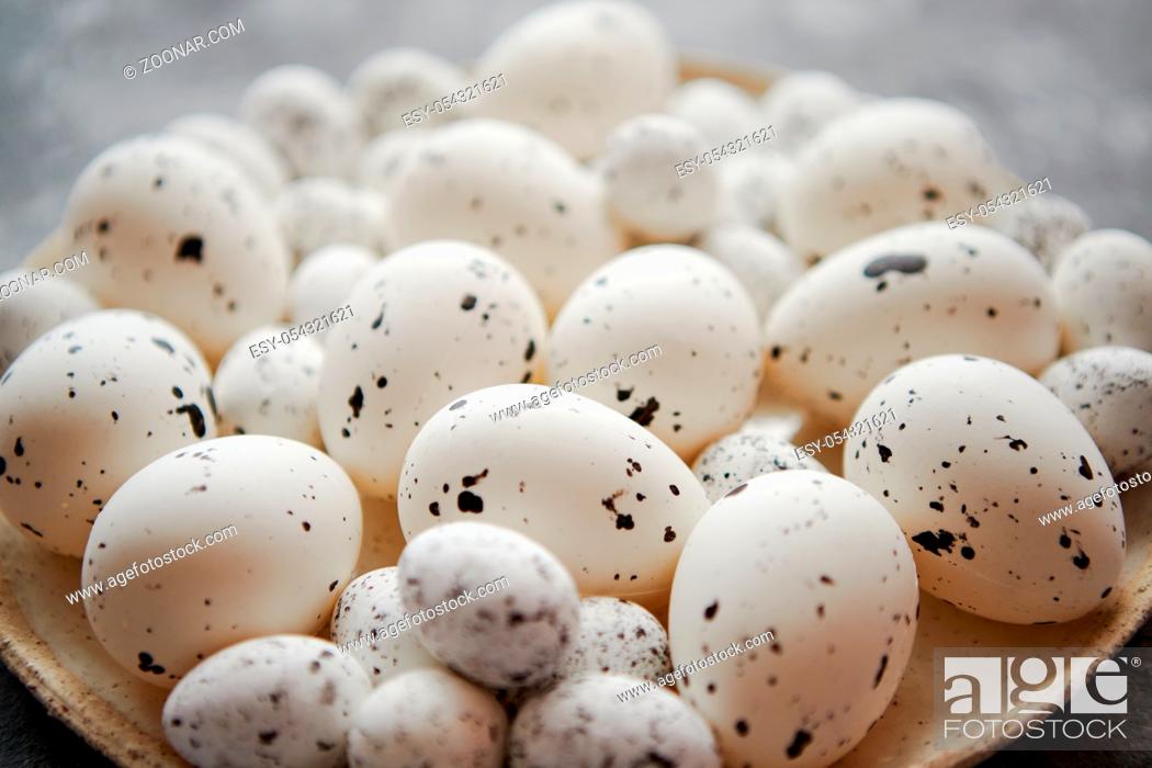 Stock Photo: Composition of white traditional dotted Easter eggs in white ceramic plate placed on gray stone background. High angle shot.