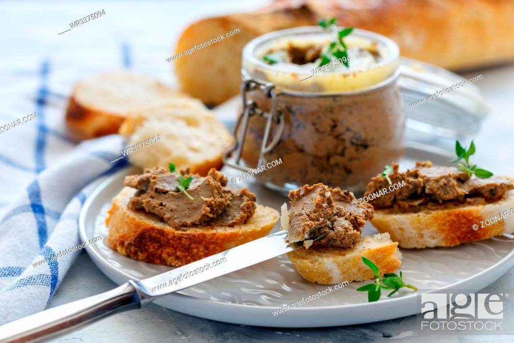 Stock Photo: Crostini with beef liver pate, thyme sprigs and a jar of pate on a white stone table, selective focus.