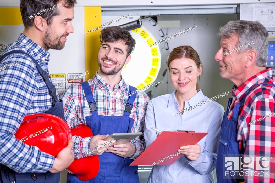 Stock Photo: Smiling staff in factory with CNC machine in background.