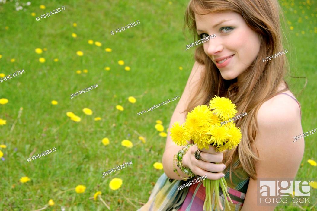 Stock Photo: young woman in a meadow with flowers in her hand.