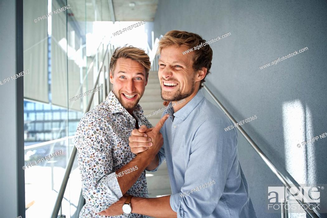 Stock Photo: Portrait of two happy young businessmen shaking hands.