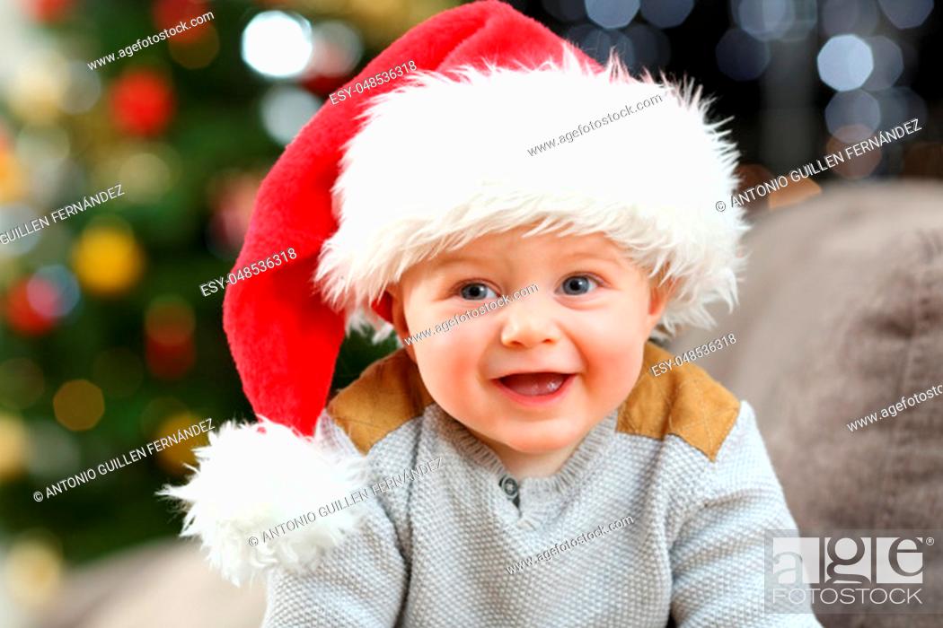Photo de stock: Baby wearing santa hat posing looking at camera at home in christmas.