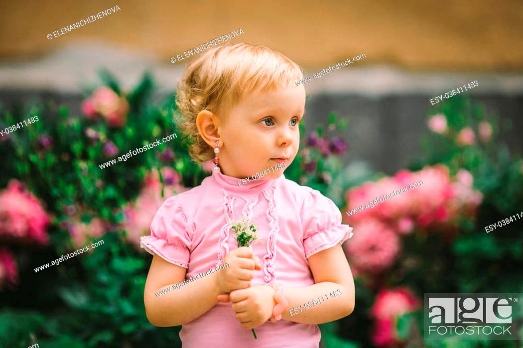 the little girl with white hair and blue eyes in a pink t-shirt poses  against flowers, Stock Photo, Picture And Low Budget Royalty Free Image.  Pic. ESY-038411483 | agefotostock