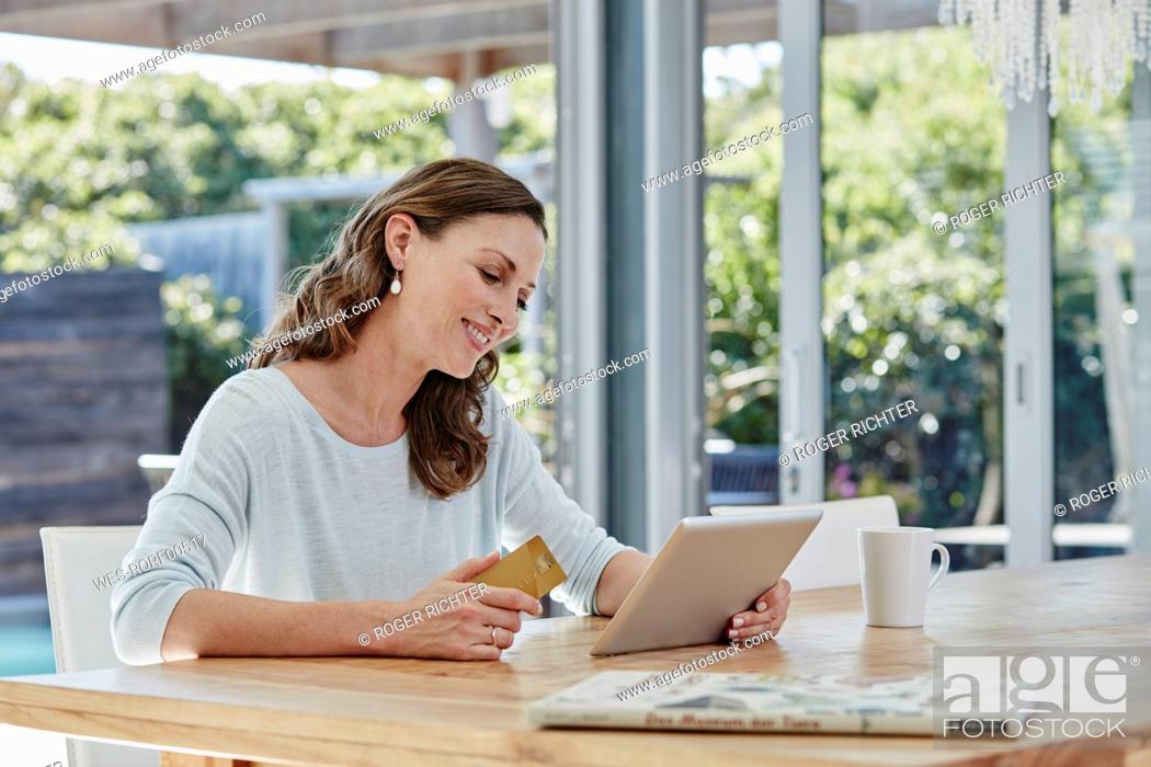 Stock Photo: Woman sitting on terrace, doing online payment with credit card.