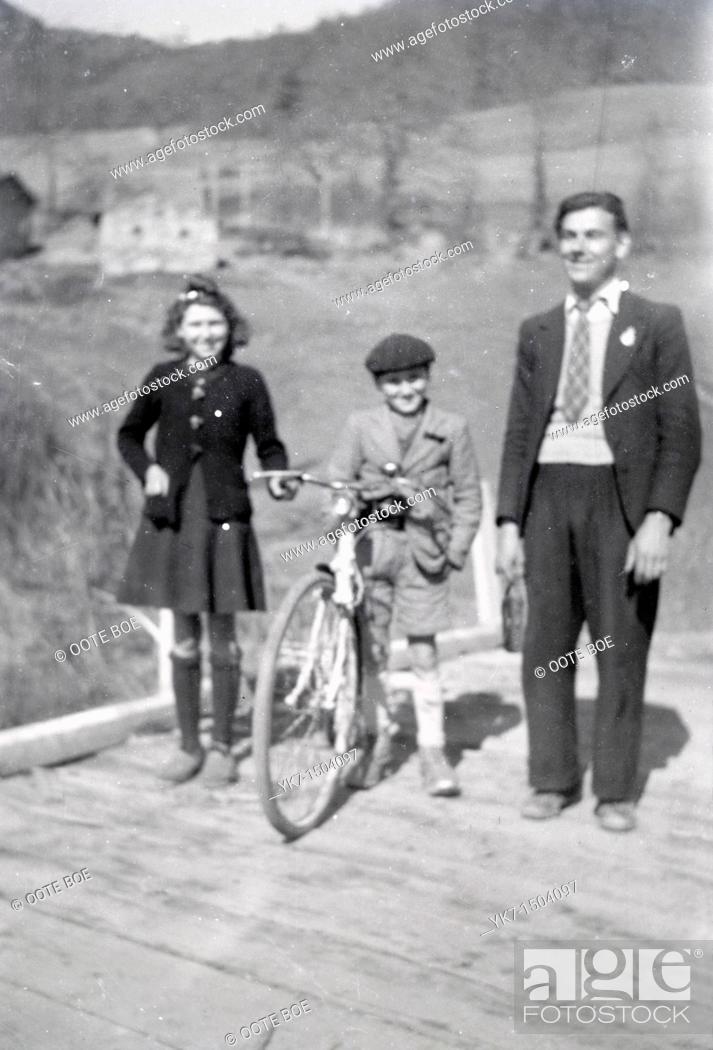 Stock Photo: adult man and two children posing on a wooden bridge in the countryside 1950s out of focus.