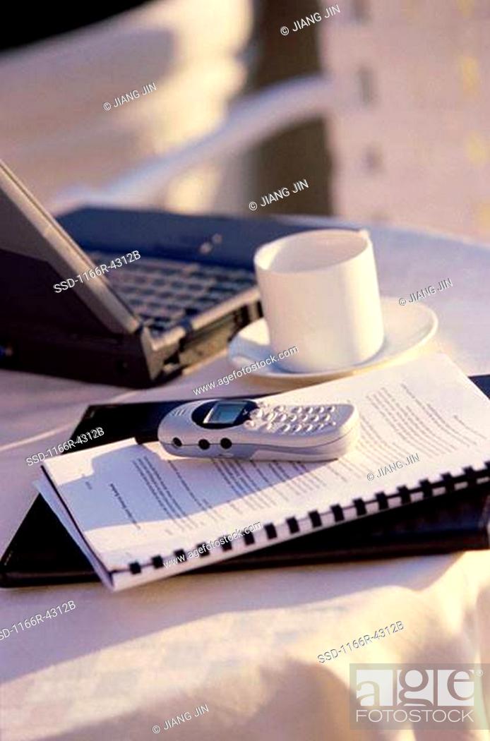 Stock Photo: Mobile phone on a notebook near a cup of coffee and a laptop.