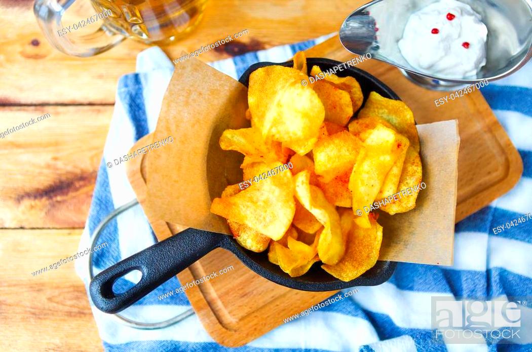 Stock Photo: Potato chips in a frying pan with garlic sauce and beer on a wooden table.
