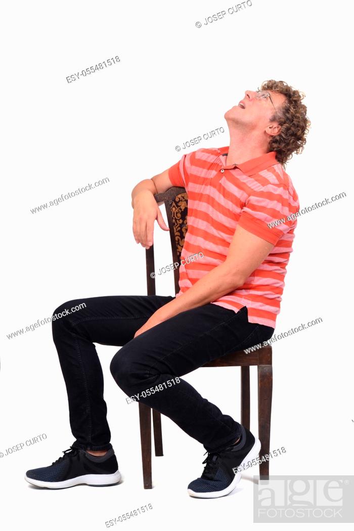 Stock Photo: full portrait of a curly man sitting sideways on white background, looking up.