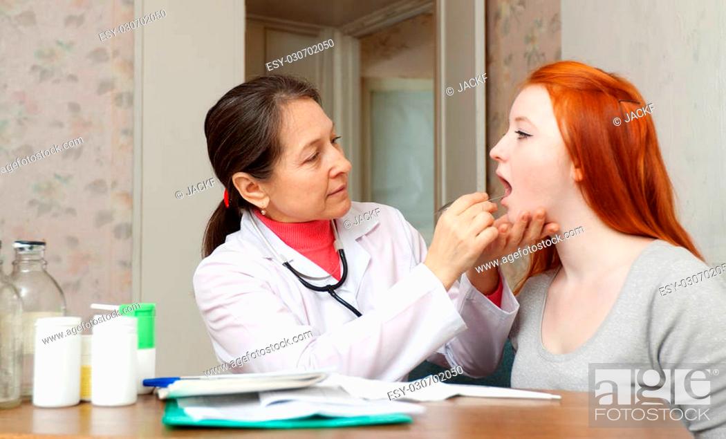 Stock Photo: Mature female doctor examining throat of teenage girl in clinic.