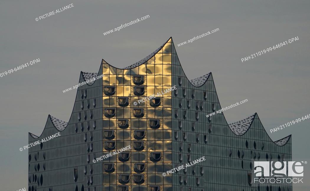 Stock Photo: 18 October 2021, Hamburg: The sunlight of the setting sun is reflected in the façade of the Elbphilharmonie. Photo: Marcus Brandt/dpa.